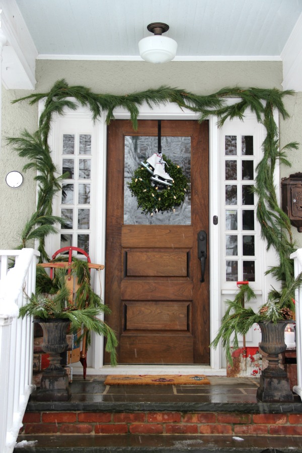 Beautiful Christmas porch with vintage sled, little metal shovel and ice skates kellyelko.com #christmasporch #christmasdecor #christmaswreath #vintagechristmas #vintagechristmasdecor #sled #kellyelko