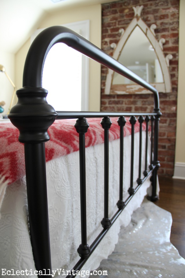 Bedroom with iron bed and exposed brick wall 