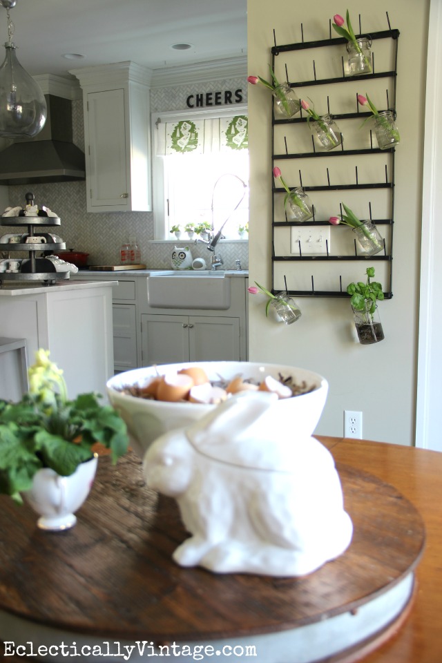 Love this kitchen and the huge bottle drying rack is so fun as a flower display plus see more creative display ideas and where to buy it! kellyelko.com #farmhouse #farmhousedecor #farmhousekitchen #platewall #vintagedecor #vintagekitchen #eclecticdecor #colorfuldecor #masonjars #springdecor 