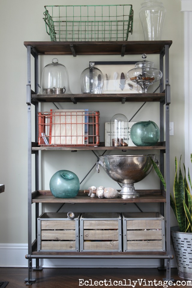 Open industrial shelf display - love the wire baskets and glass cloches kellyelko.com #spring #springdecor #springdecorating #springcrafts #hometour #housetour #eclectichome #farmhousedecor #fixerupperstyle #shelfie #farmhousestyle #vintagedecor #vintagehome #kellyelko #shelfstyling #industrialdecor 