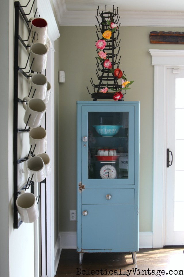 Vintage blue medical cabinet looks great in a kitchen kellyelko.com #bottlerack #springdecor #vintagedecor #aqua #eclecticdecor #kellyelko