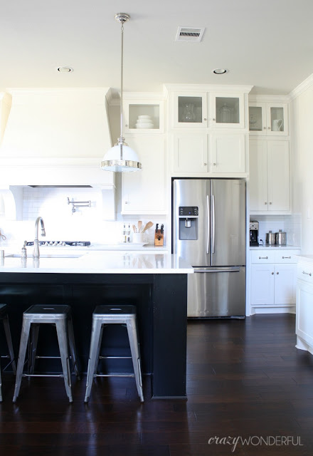 Love this white kitchen with black island and metal stools kellyelko.com