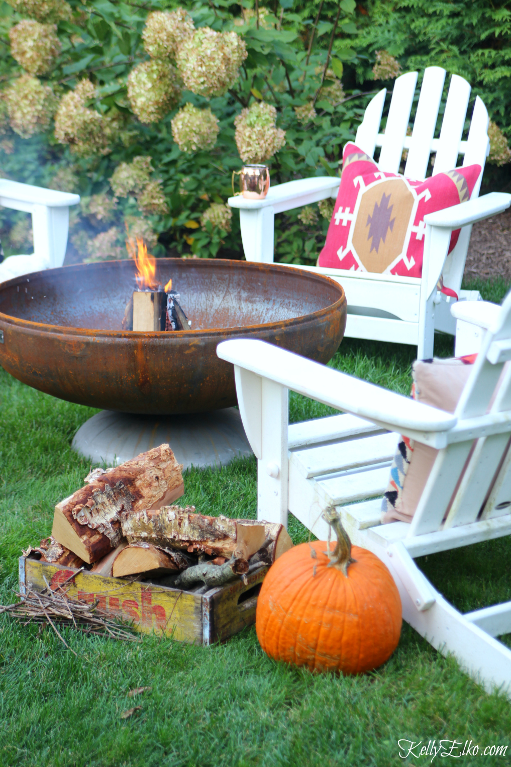 Love the patina on this fire pit surrounded by adirondack chairs and cozy throw and pillows kellyelko.com