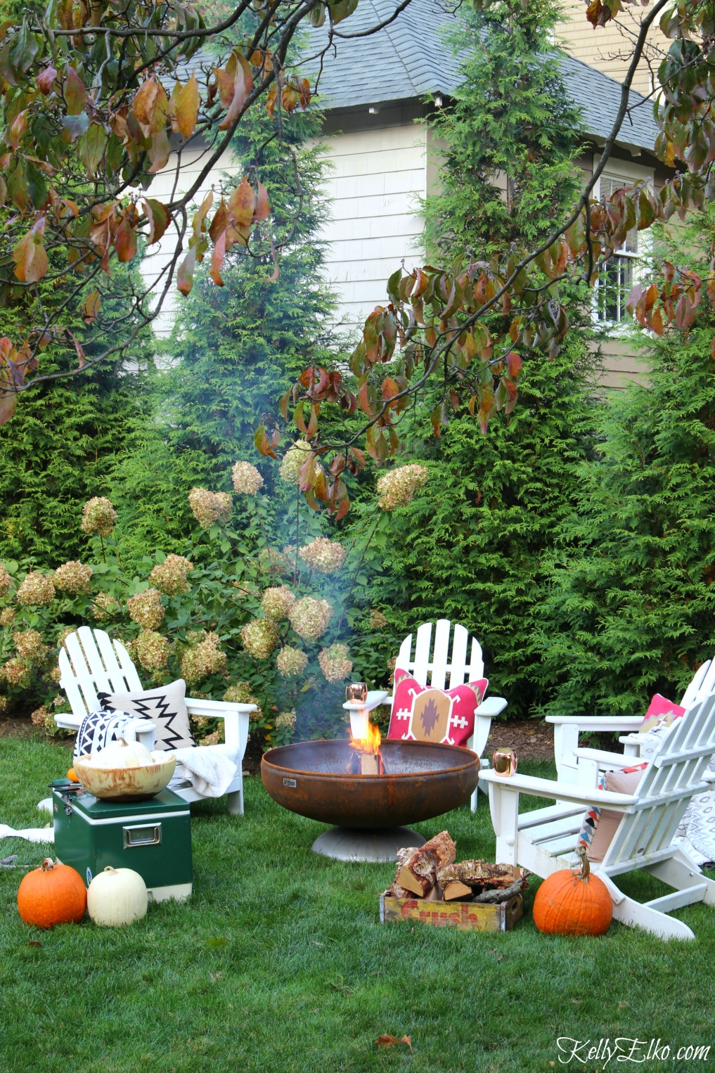 Love this fire pit surrounded by adirondack chairs piled high with boho throws and pillows kellyelko.com