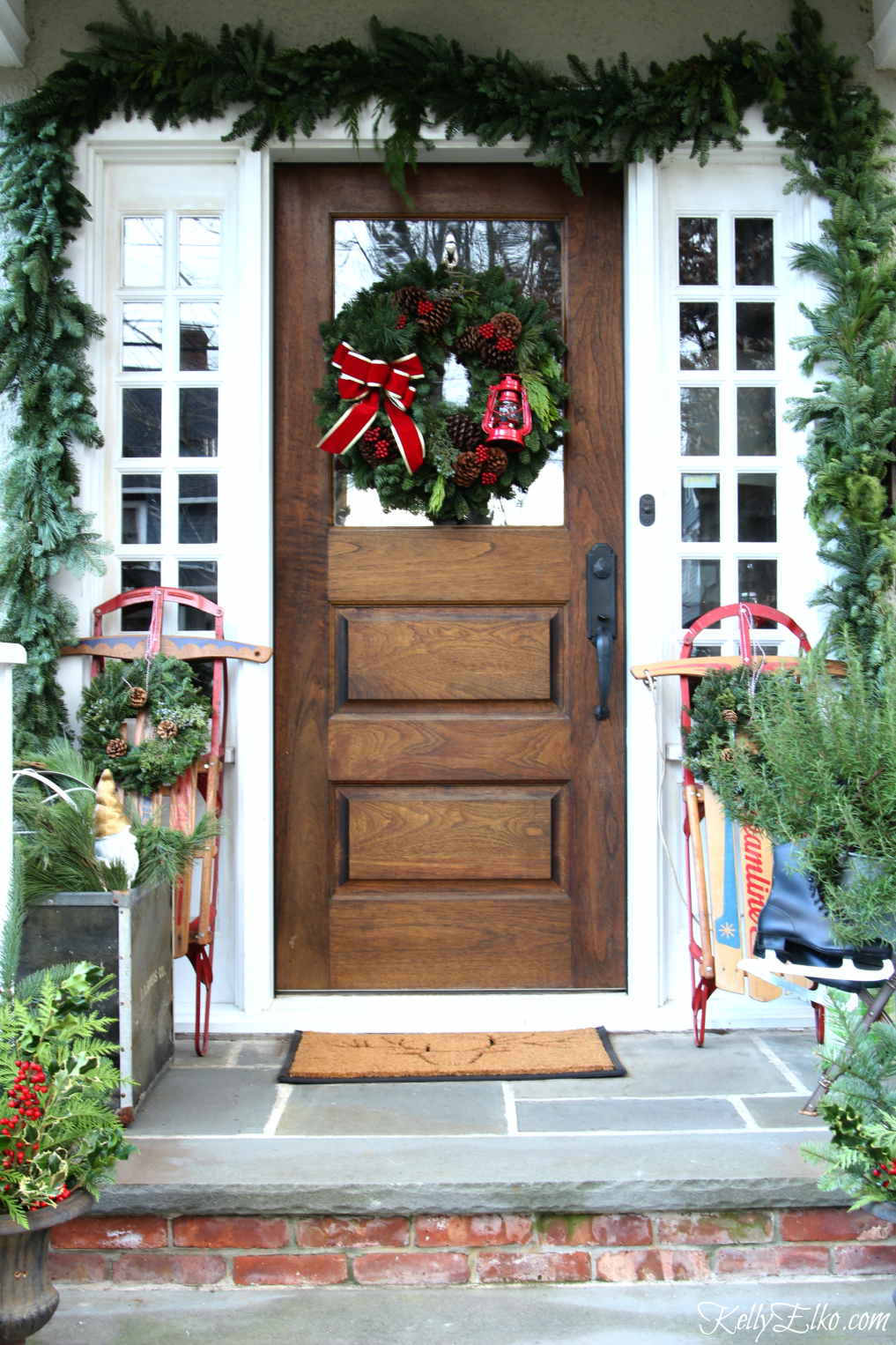 Classic Christmas porch with a pair of vintage sleds kellyelko.com #christmas #christmasporch #outdoorchristmasdecor #christmaswreath #christmasgarland #vintagechristmas #classicchristmas #farmhousechristmas 