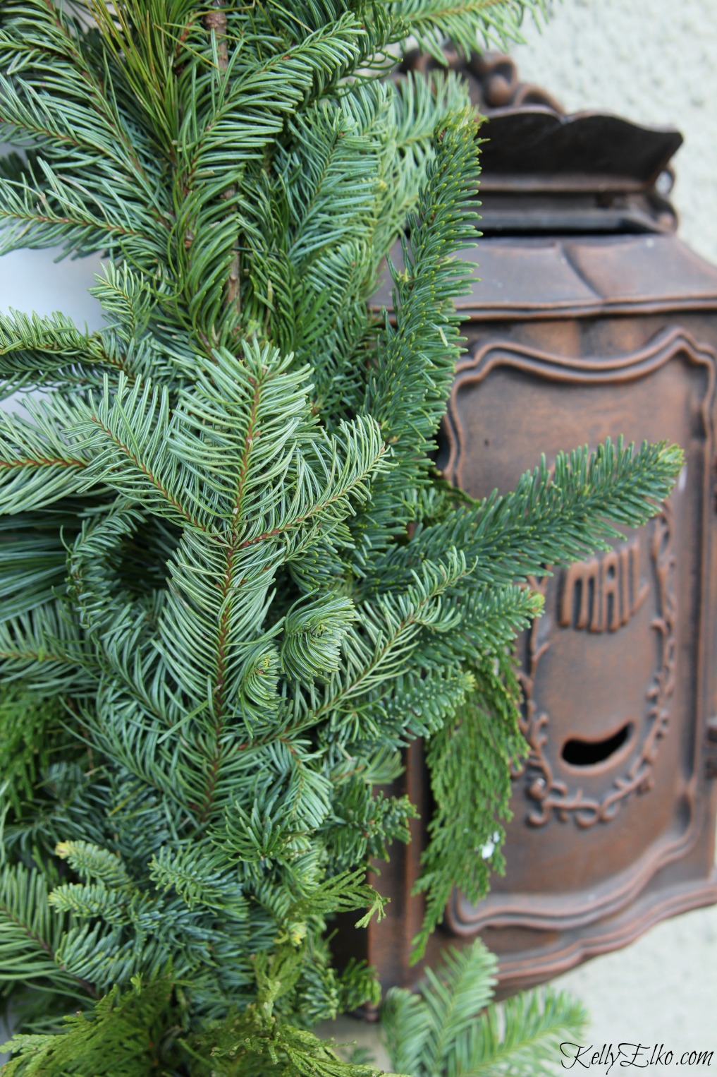 Thick and lush garland surrounds the front door of this beautiful Christmas porch kellyelko.com