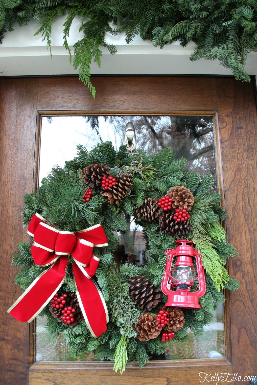 Red lantern Christmas wreath on this beautiful front door kellyelko.com