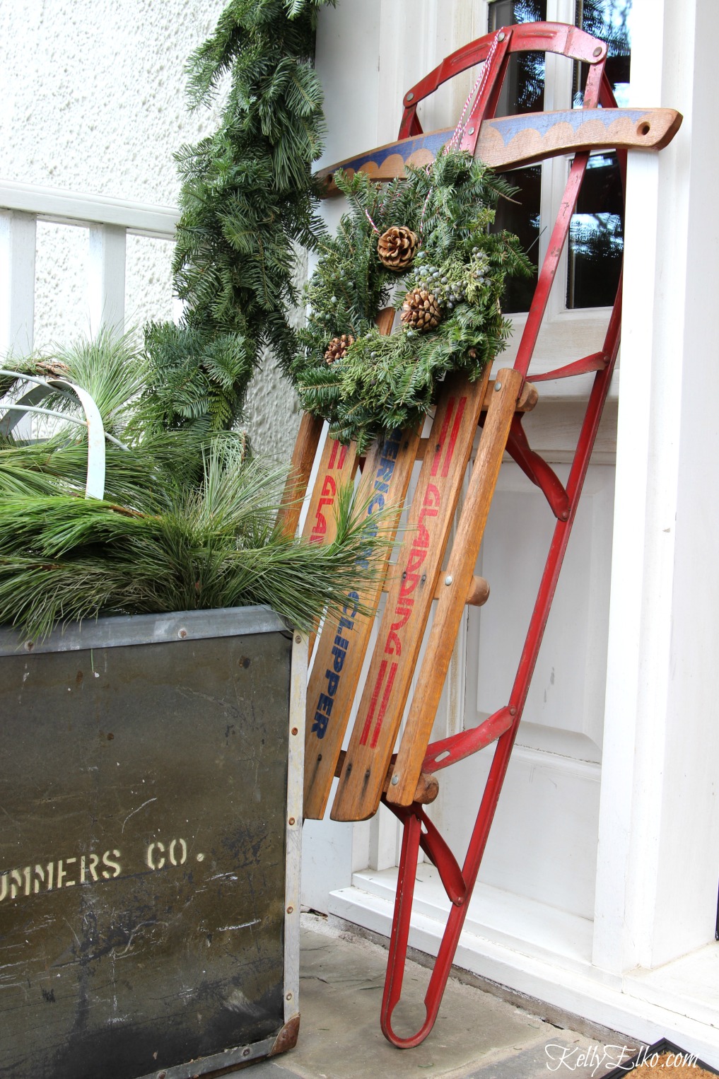 Vintage wood sled with wreath on this welcoming Christmas porch kellyelko.com