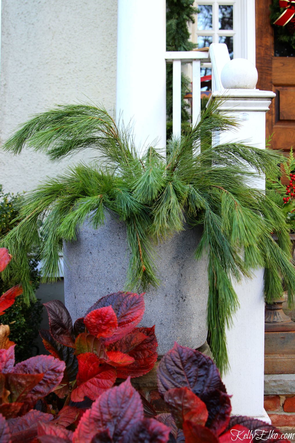 Love this Christmas front porch with planters filled with fresh greens kellyelko.com