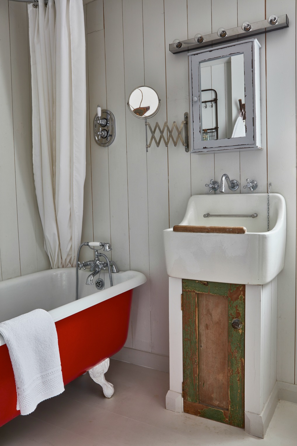 An old claw foot tubs gets a coat of red paint in this cottage bathroom with planked white walls kellyelko.com