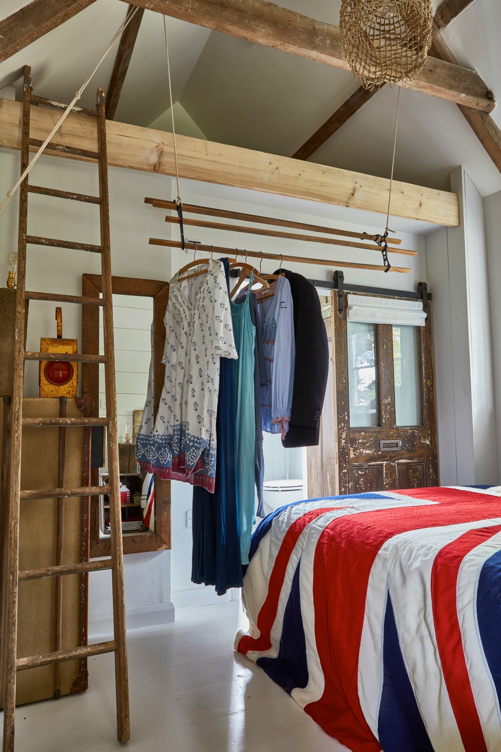 Cottage bedroom complete with old ceiling beams and a pulley system in place of a closet kellyelko.com