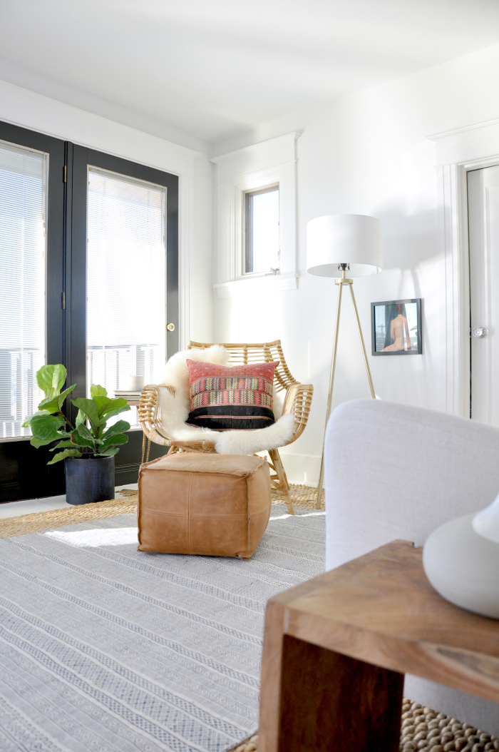 Cozy reading nook in the bedroom - love the rattan chair and leather pouf