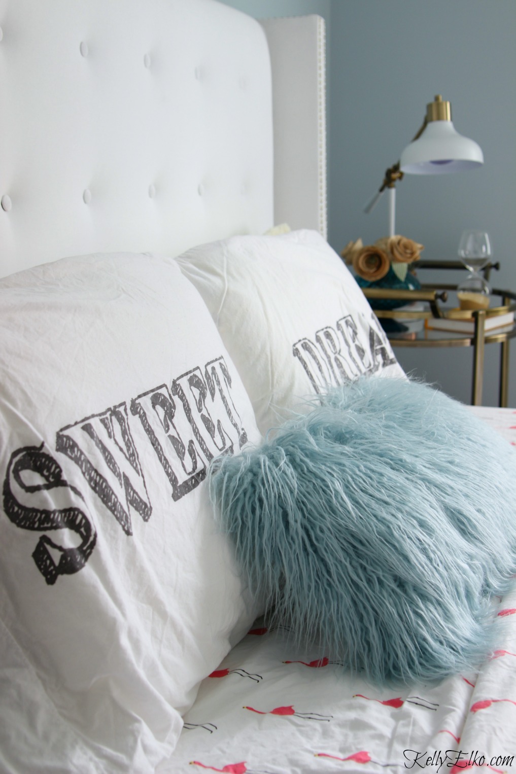 Love this glam tufted white headboard and fun mix of pillows and bedding kellyelko.com