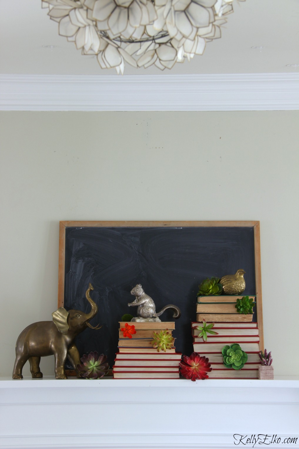 Vintage winter mantel - love the stacks of books with succulents and collection of brass animals kellyelko.com