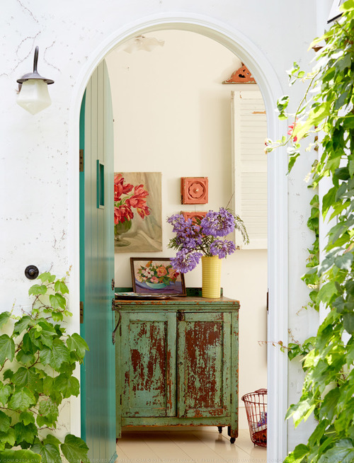 Teal arched front door opens into a colorful entry 