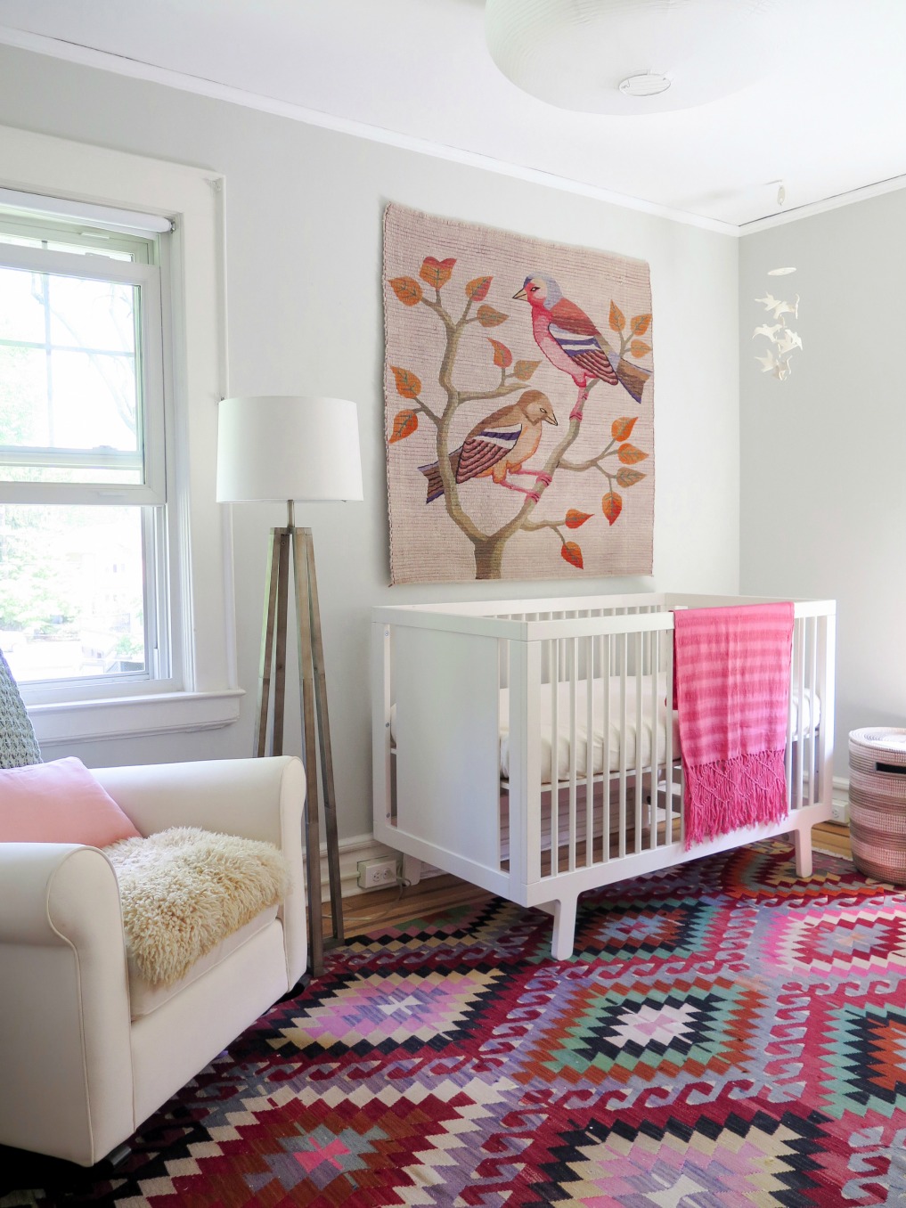 Pink nursery - love the vibrant rug and bird tapestry