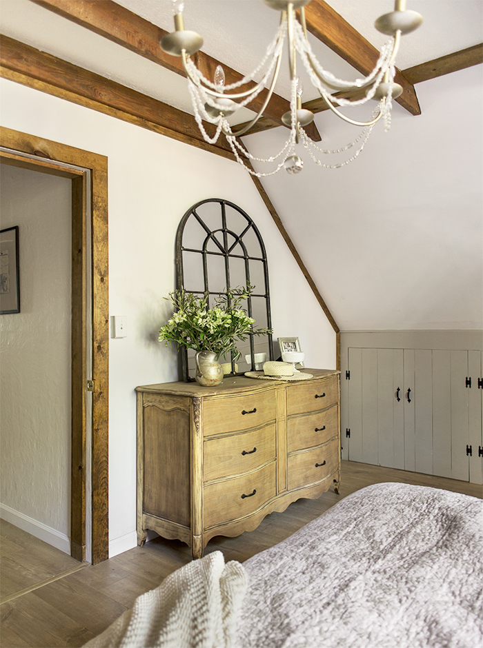 Rustic wood beams add character to a white bedroom