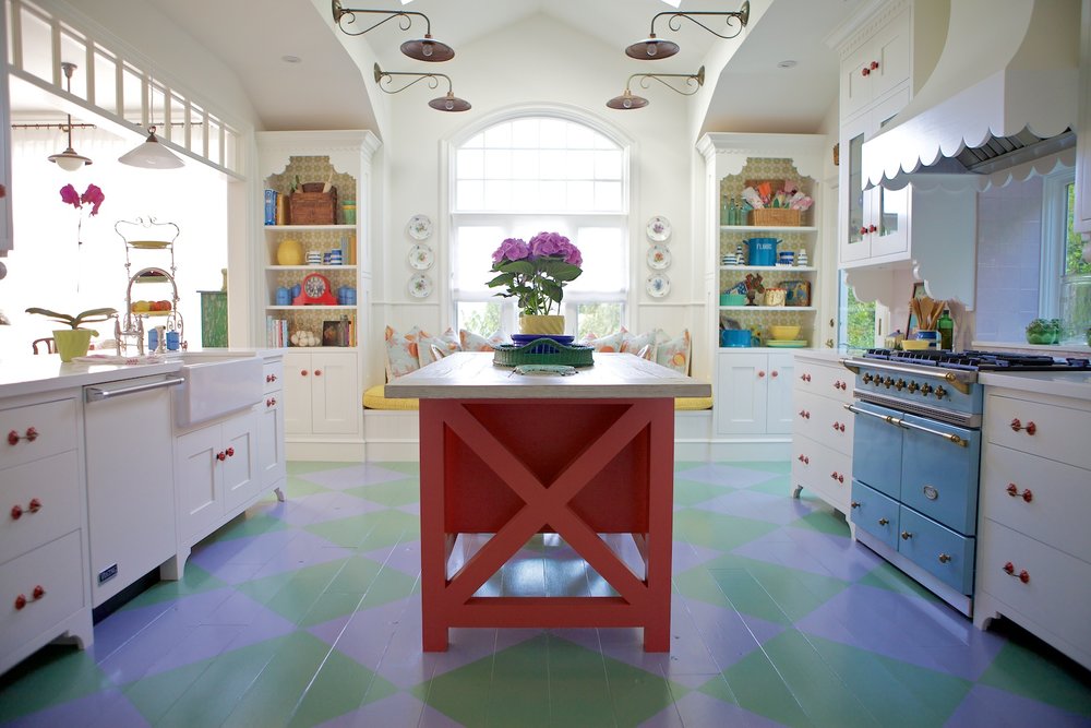 Colorful kitchen with painted wood floor, red island and blue stove 