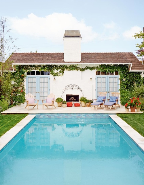 Stunning pool house with blue french doors and climbing vines