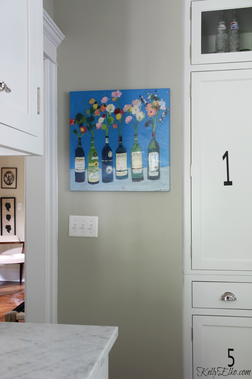 Colorful wine bottle flower art brings life to a white kitchen kellyelko.com