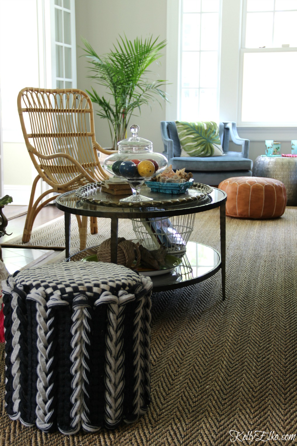 Love this eclectic living room filled with unique furniture finds like a rattan chair, wool ottoman and leather pouf kellyelko.com