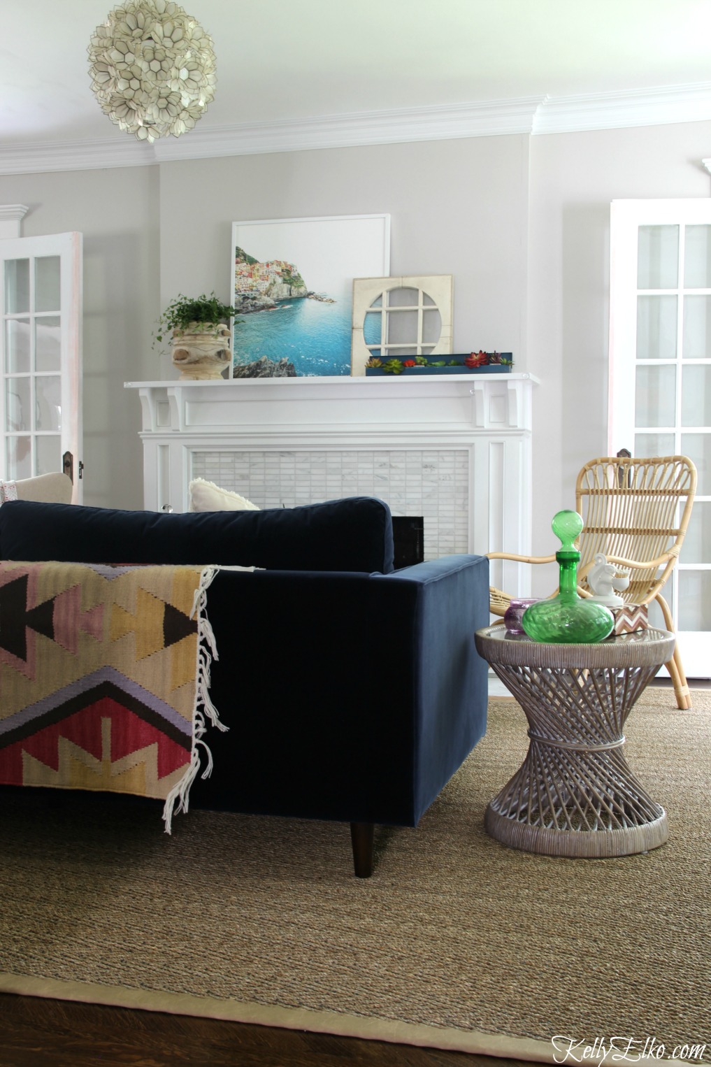 Colorful living room - love the blue velvet sofa and colorful rug draped over back and the capiz shell chandelier kellyelko.com