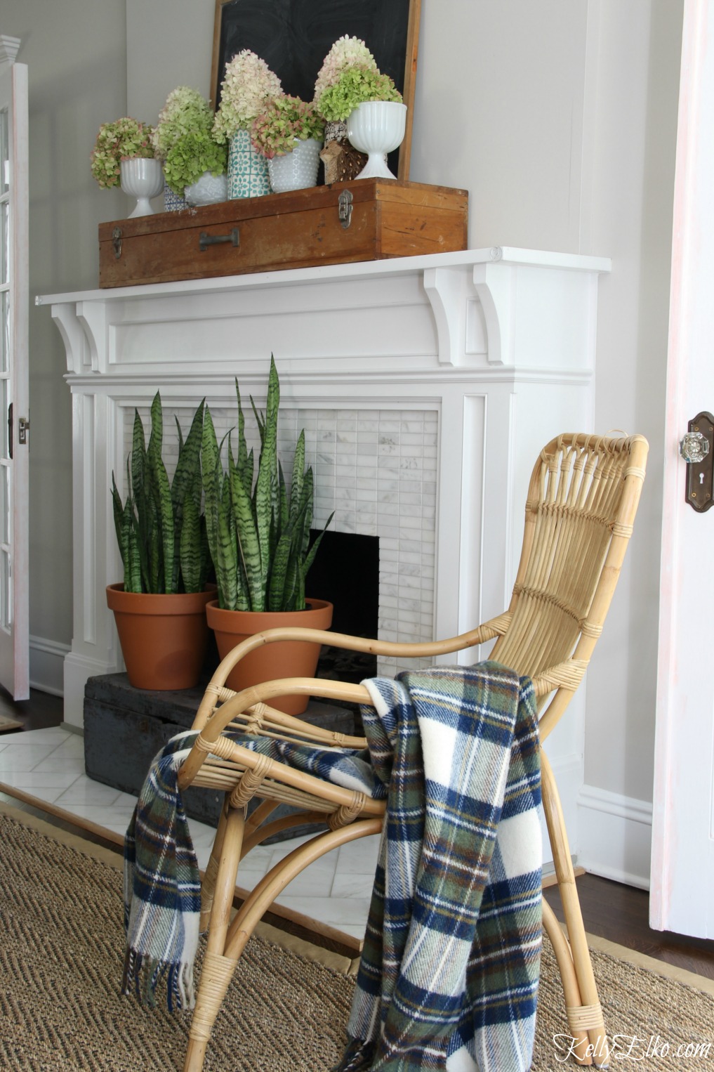 Love the boho feel of this living room with rattan chair, cozy wool throw and hydrangea filled mantel kellyelko.com