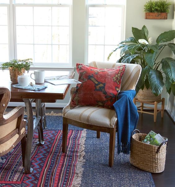 Layered rugs and pillows in reds and blues warm up this dining room kellyelko.com