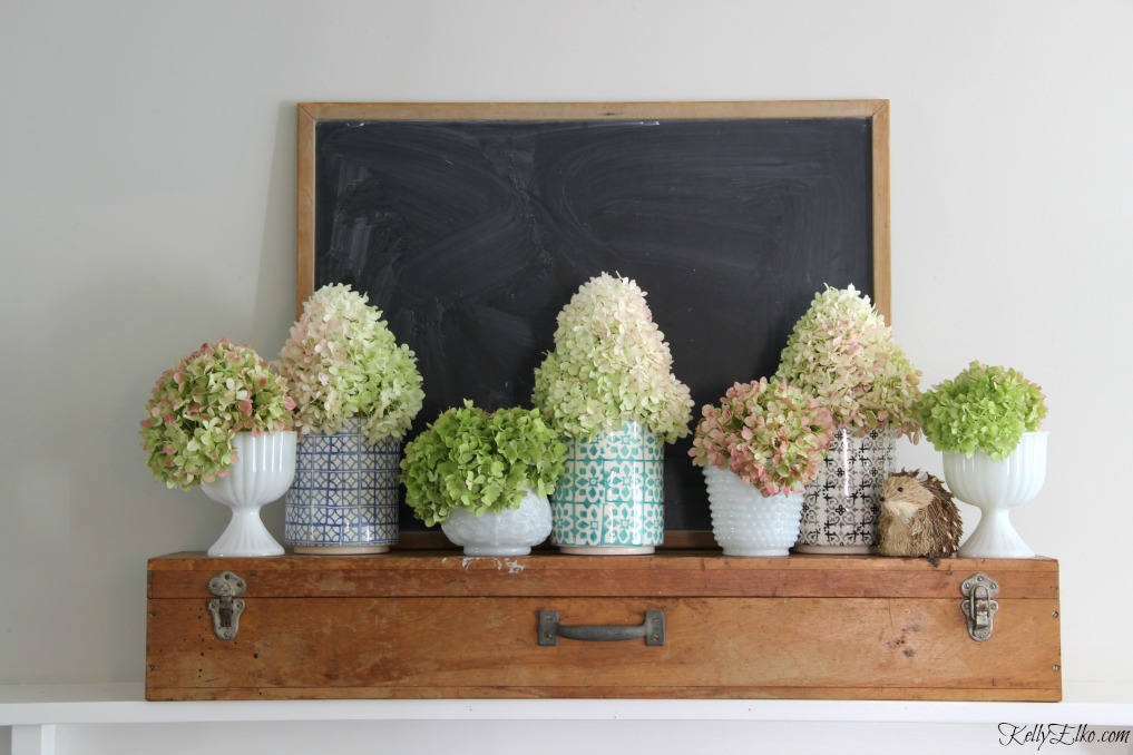 Beautiful mantel of hydrangeas in colorful vases mixed with vintage milk glass kellyelko.com