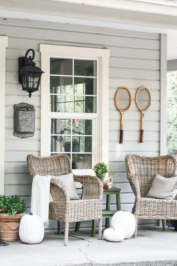 Farmhouse tour - love the wicker chairs and old tennis racquet art on the porch