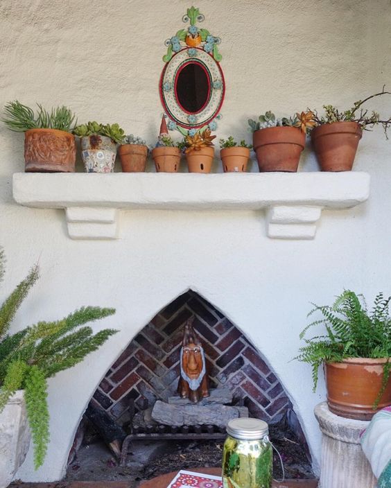 Outdoor fireplace with cute collection of plants in terra cotta pots