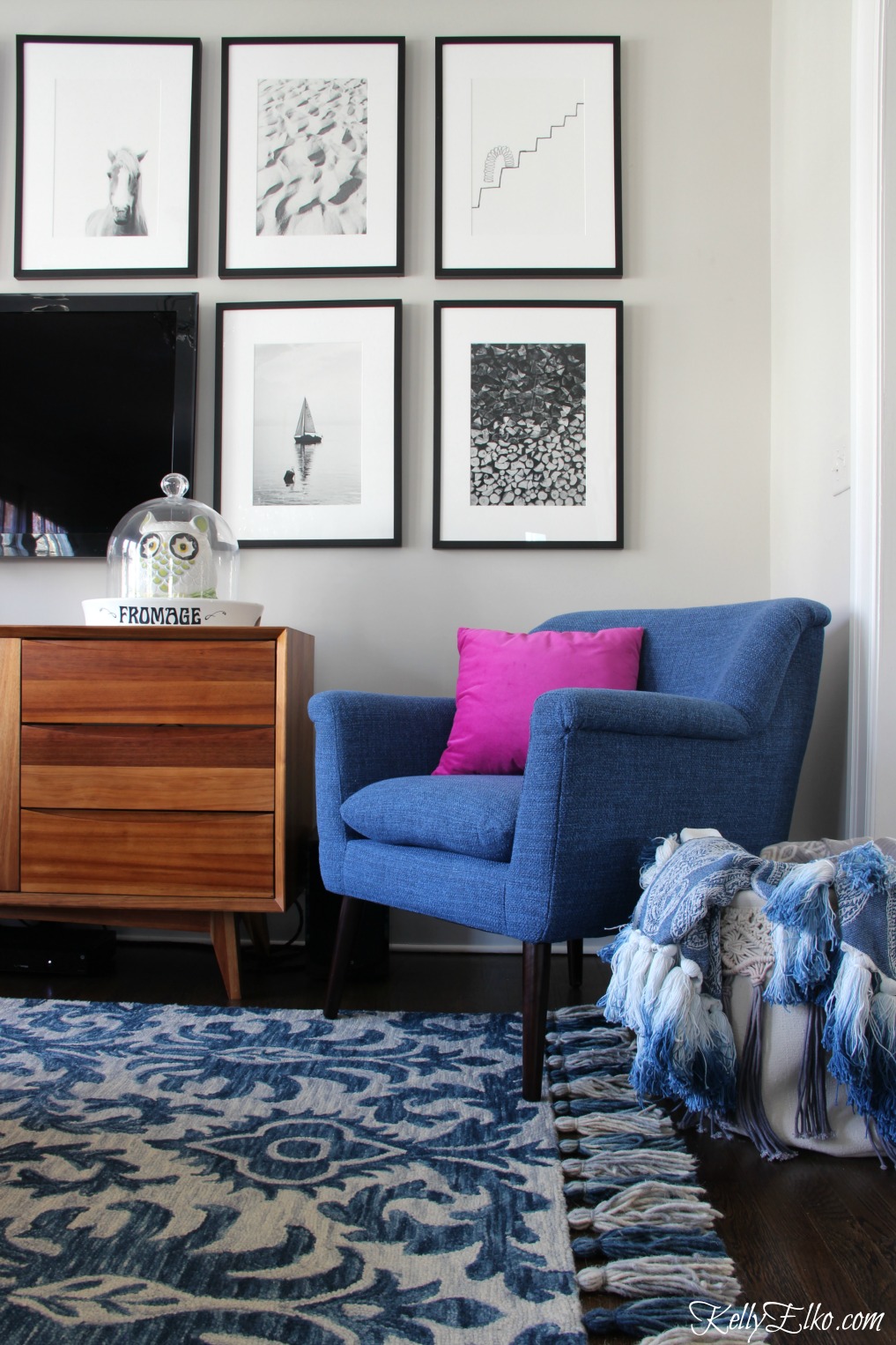 Cozy family room with blue tassel rug and chair - love the black and white photography displayed around the TV kellyelko.com #photography #art #gallerywall #homedecor #bohodecor