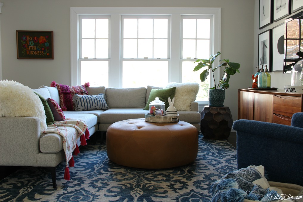 Beautiful and cozy family room with sectional sofa, leather ottoman, blue tassel rug and an eclectic mix of pillows and throws kellyelko.com #familyroom #homedecor #decorate #ottoman #sectional #bohodecor