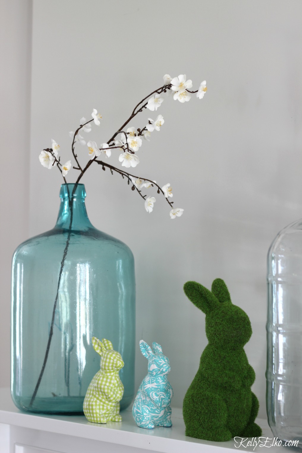 25 Spring Decorating Ideas - love this mantel with vintage glass demijohns and colorful bunnies kellyelko.com #spring #springdecor #homedecor #mantel #springmantel #vintagedecor #easterbunny