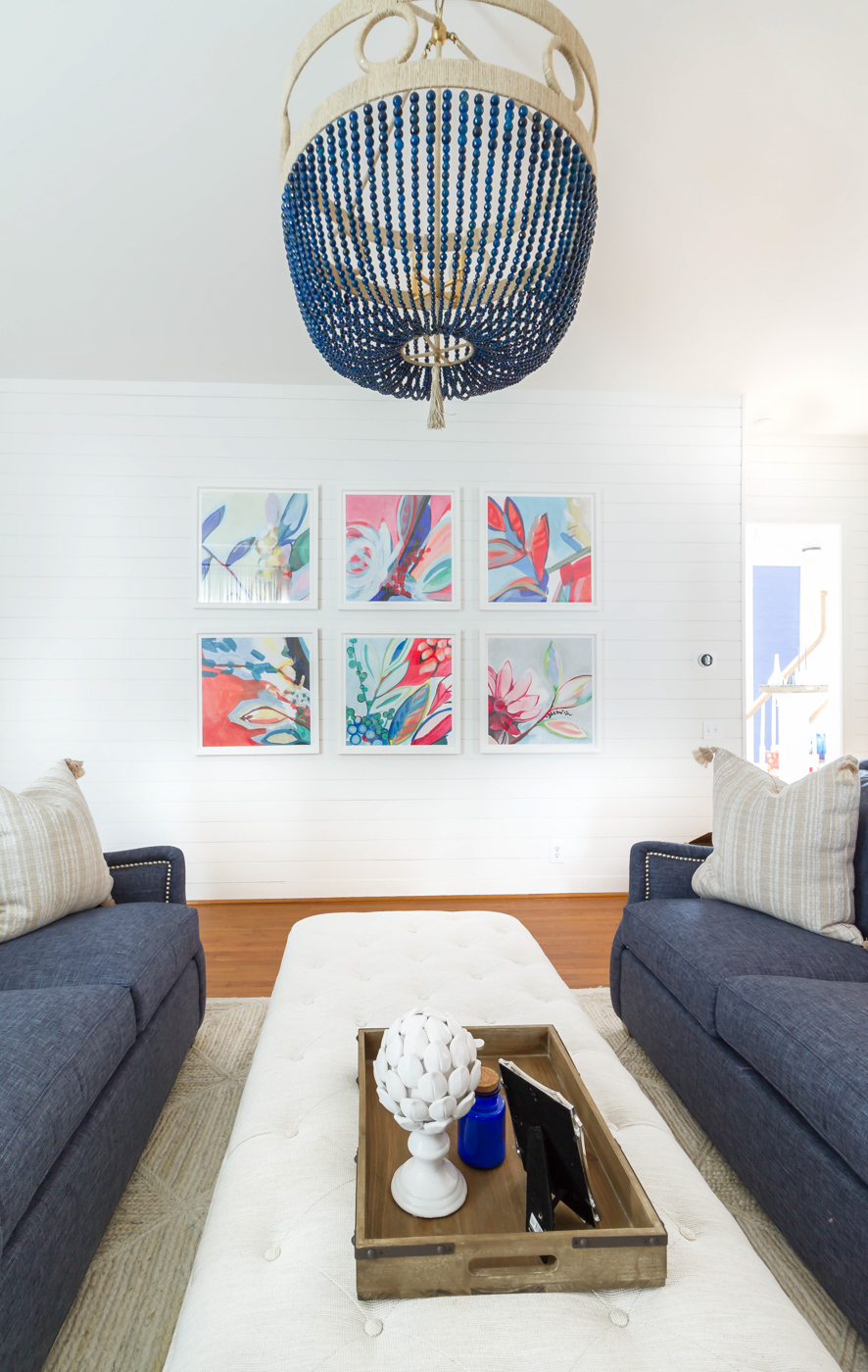 Eclectic Home Tour - love the white shiplap walls as a backdrop for a colorful gallery wall and statement chandelier #art #chandelier #lighting #livingroom