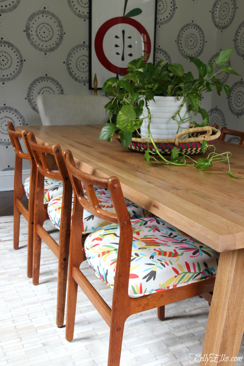 This eclectic dining room mixes Danish modern chairs with colorful otomi fabric and an Article dining table in solid oak kellyelko.com #diningroom #diningroomdecor #diningroomfurniture #midcenturymodern #midcentury #bohostyle #otomi #vintagestyle #interiordecor 