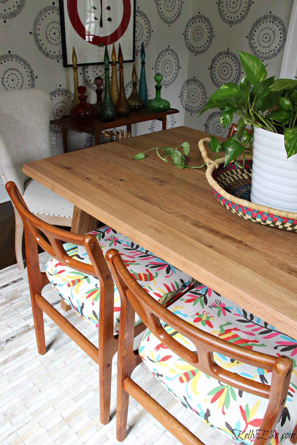This eclectic dining room mixes Danish modern chairs with colorful otomi fabric and an Article dining table in solid oak kellyelko.com #diningroom #diningroomdecor #diningroomfurniture #midcenturymodern #midcentury #bohostyle #otomi #vintagestyle #interiordecor 