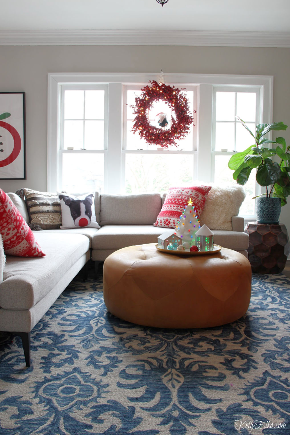 Love this cozy Christmas family room with Loloi rug and huge leather ottoman kellyelko.com #bohochristmas #christmaswreath #leatherottoman #christmasfamilyroom #redchristmas #christmasdecor #christmadecorations