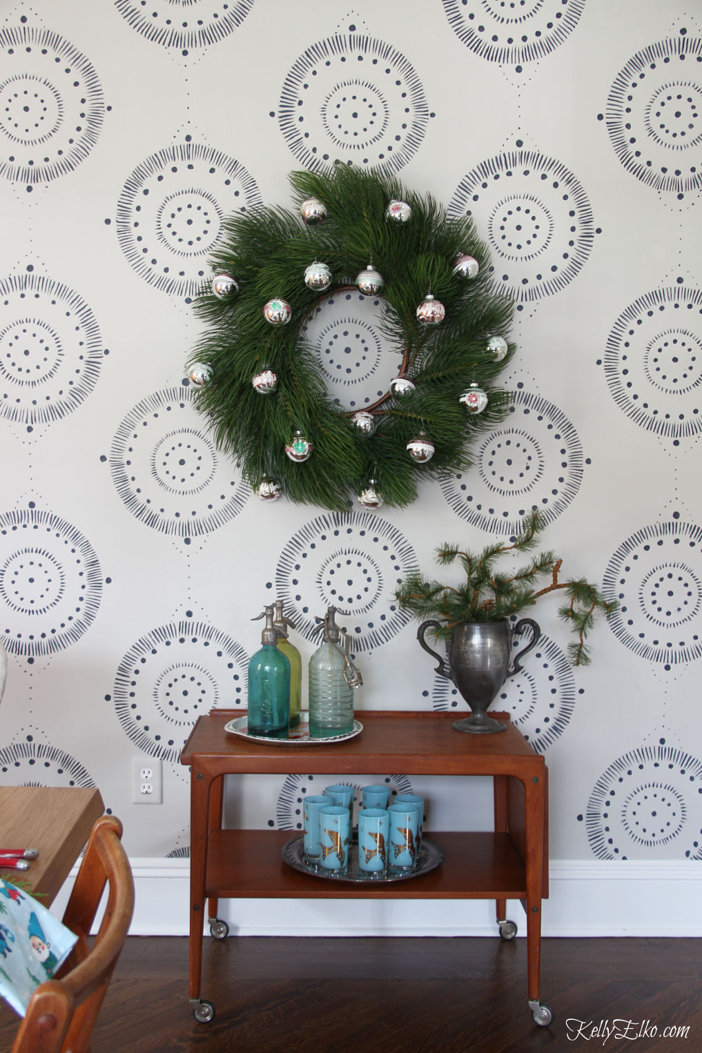 Love this Danish modern bar cart in a Christmas dining room kellyelko.com #christmaswreath #christmasdecor #christmasdecorations #shinybrites #vintagedecor #vintagechristmas #wallmural #ltkholiday