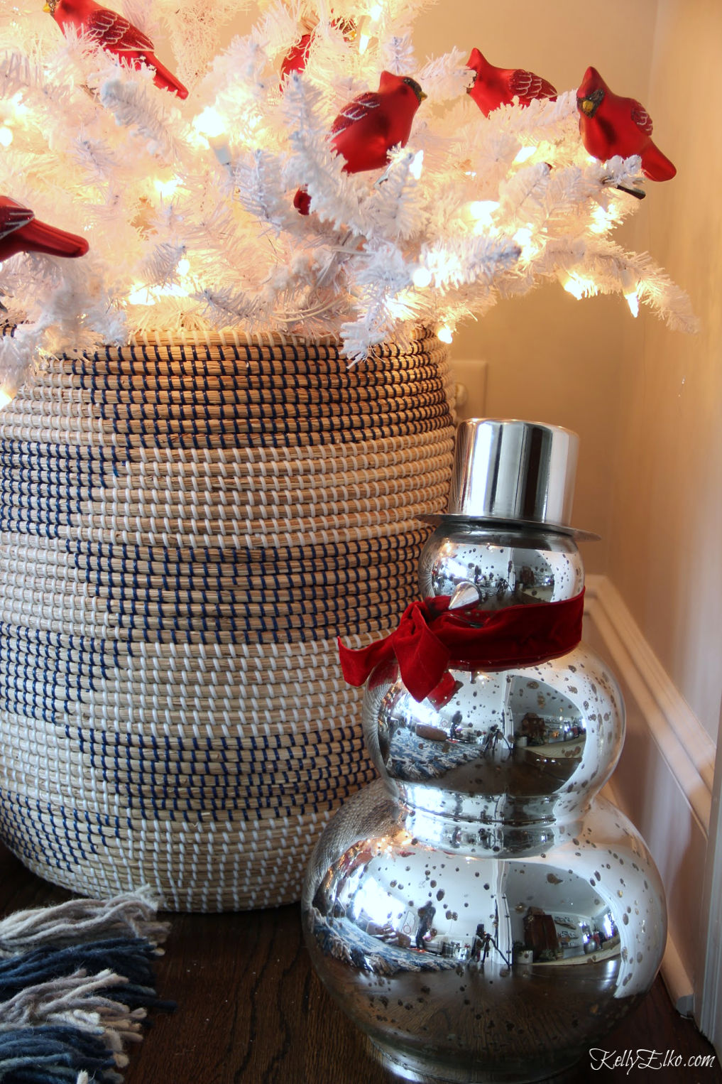 Love this white Christmas tree with basket tree skirt and flock of red cardinal ornaments #kellyelko.com #whitetree #christmastree #christmasdecor #diychristmas #christmasdecorating
