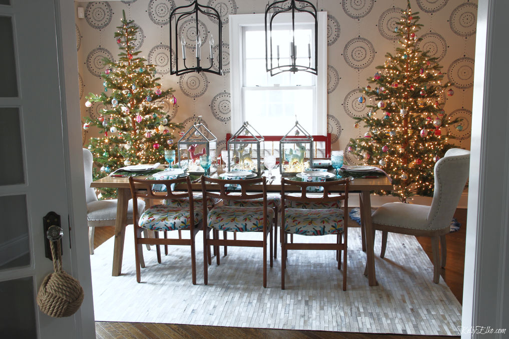 Love this dining room decked out for Christmas with a pair of sparse Christmas trees covered in vintage ornaments kellyelko.com