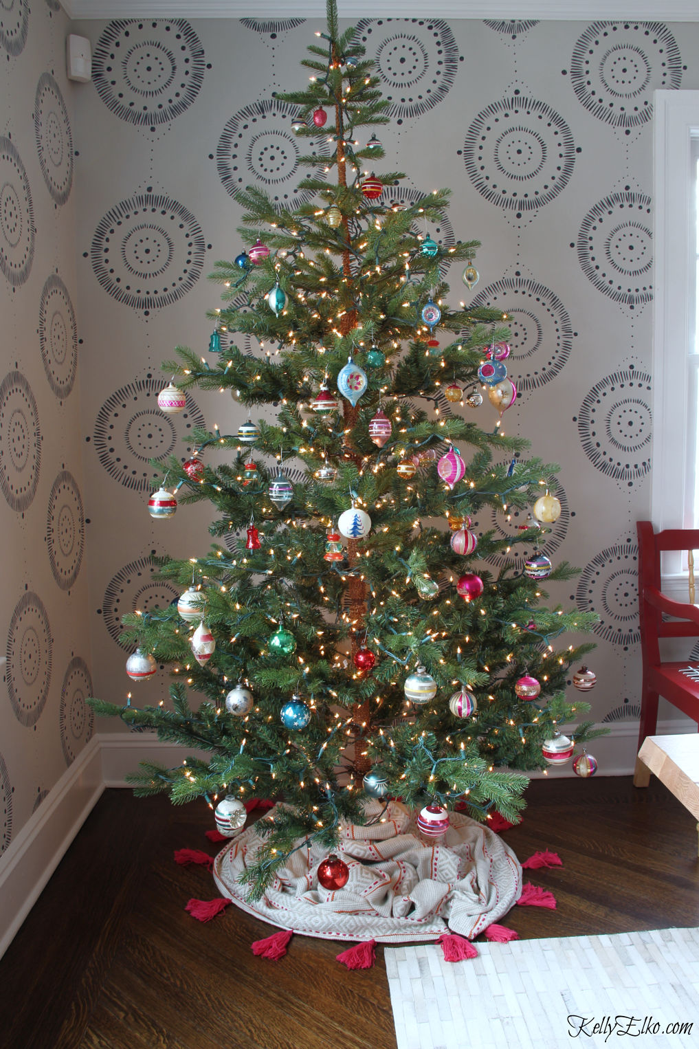 Love this sparse Christmas tree filled with vintage Shiny Brite ornaments and how cool is the tassel tree skirt kellyelko.com #christmastree #christmasdecor #christmasdecorations #christmaslights #diychristmas #treeskirt 