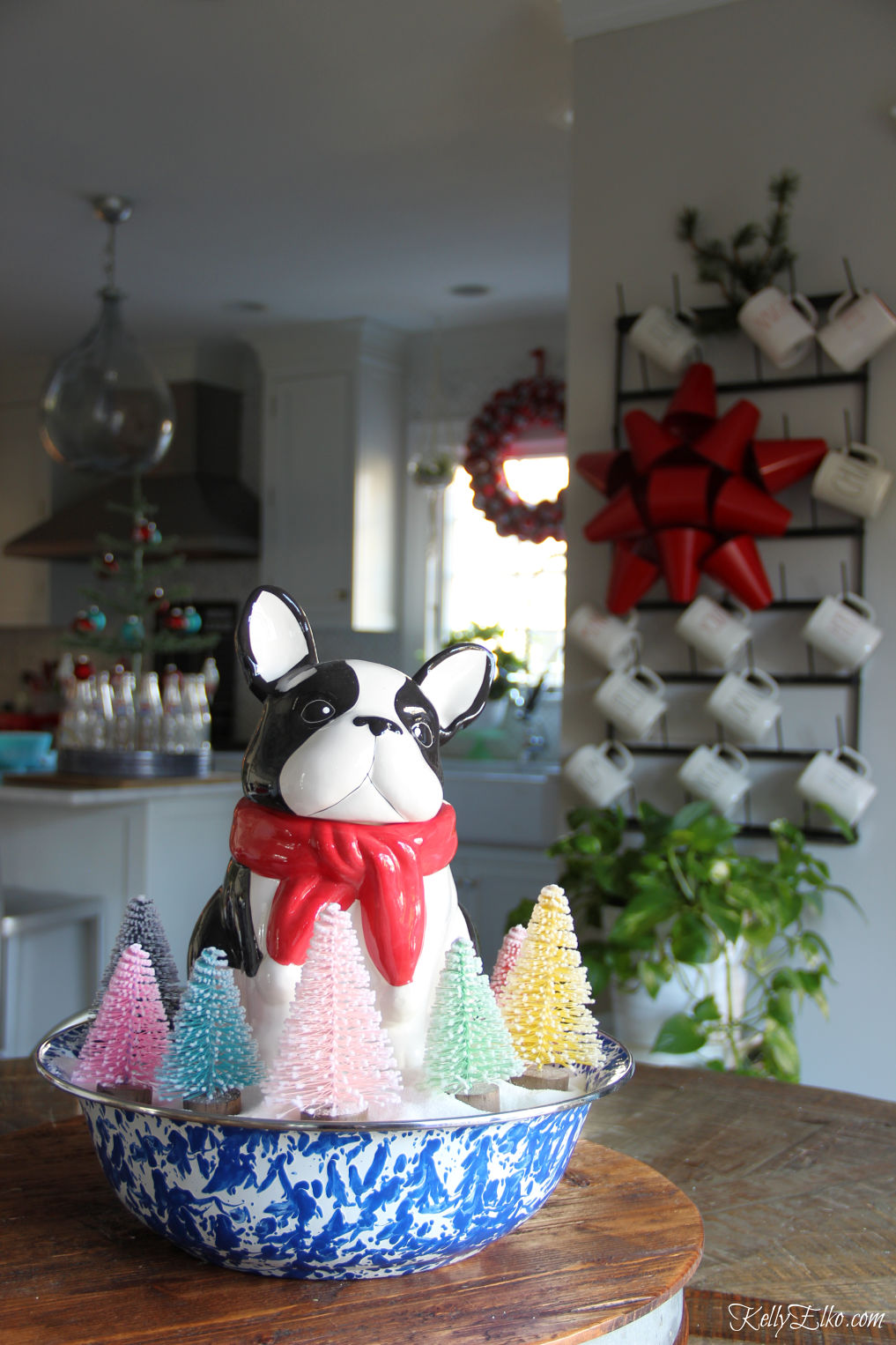 Love her festive Christmas kitchen and this adorable little dog surrounded by bottle brush trees centerpiece kellyelko.com #christmas #christmascenterpiece #christmasdecor #christmastrees #christmasdecorating #christmaskitchen #frenchbdulldog #vintagechristmas 