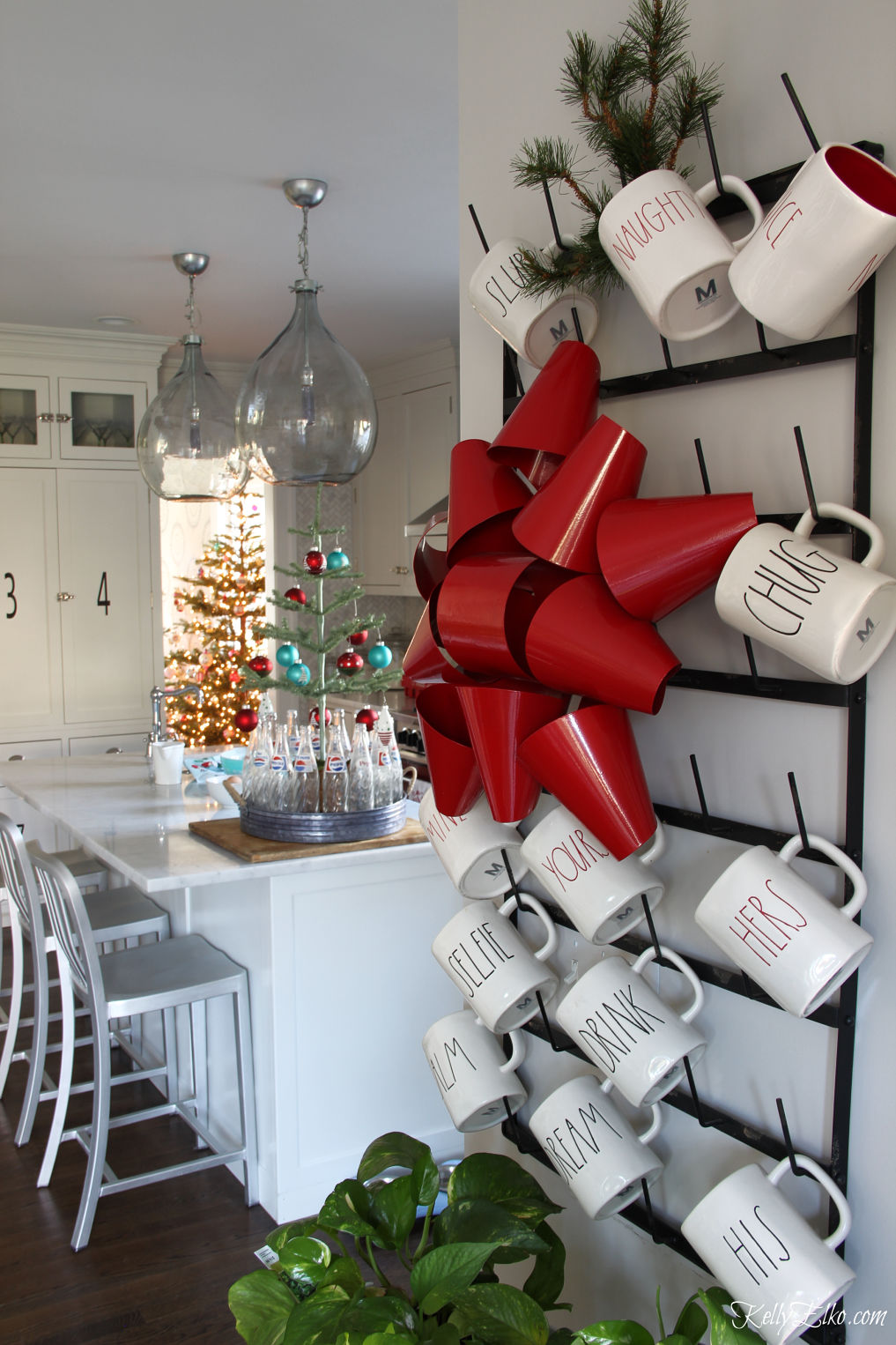 Love this red teal Christmas kitchen and the giant rack of Rae Dunn mugs kellyelko.com #christmas #christmaskitchen #christmasdecor #christmasdecorating #vintagechristmas #farmhousechristmas 