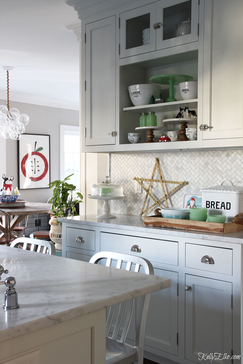 Love the open shelves in this Christmas kitchen kellyelko.com #whitekitchen #openshelves #farmhousekitchen #christmaskitchen #christmasdecor #christmasdecorations #vintagechristmas