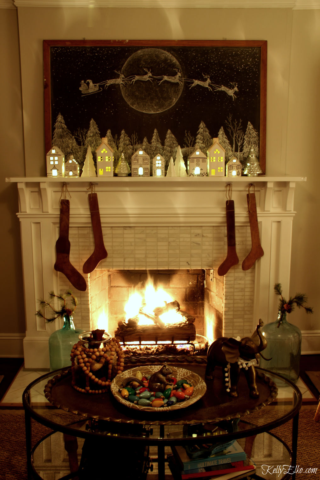 Don't miss this Christmas home tour at night! Love the glowing Christmas village and roaring fire kellyelko.com #christmas #christmslights #christmasdecor #christmasdecorating #christmasdiningroom #vintagechristmas #retrochristmas #christmastrees #christmasmantel #