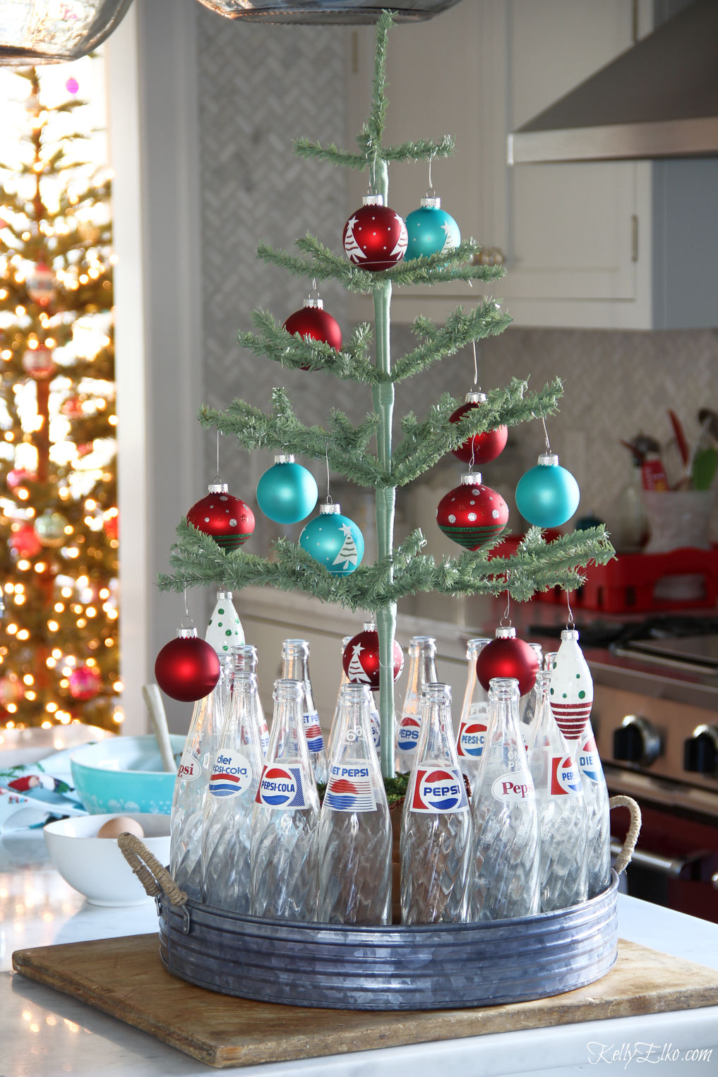 Love this feather tree and vintage Pepsi bottle Christmas display kellyelko.com #christmastree #vintagechristmas #christmaskitchen #christmasdecor #christmasdecorations 