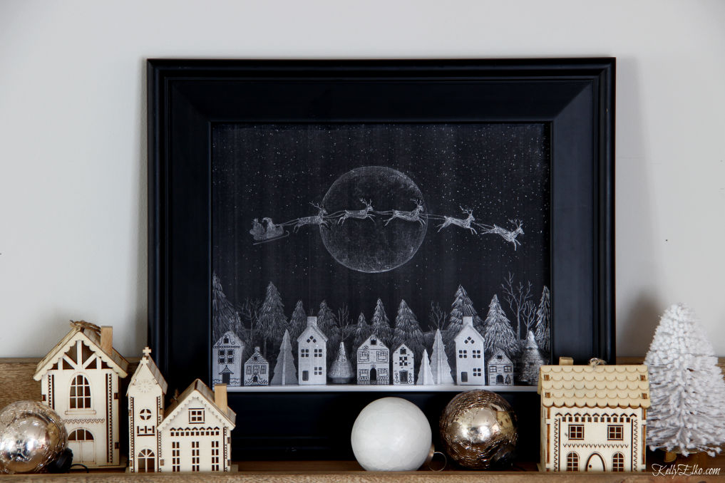 I love this free printable chalkboard Christmas Santa and reindeer flying over a village of houses kellyelko.com #chalkboard #chalkboardart #chalkart #freeprintables #printables #freeart #art #santa #christmas #christmasart #christmasprintable #christmasdecor #christmasdecorating 