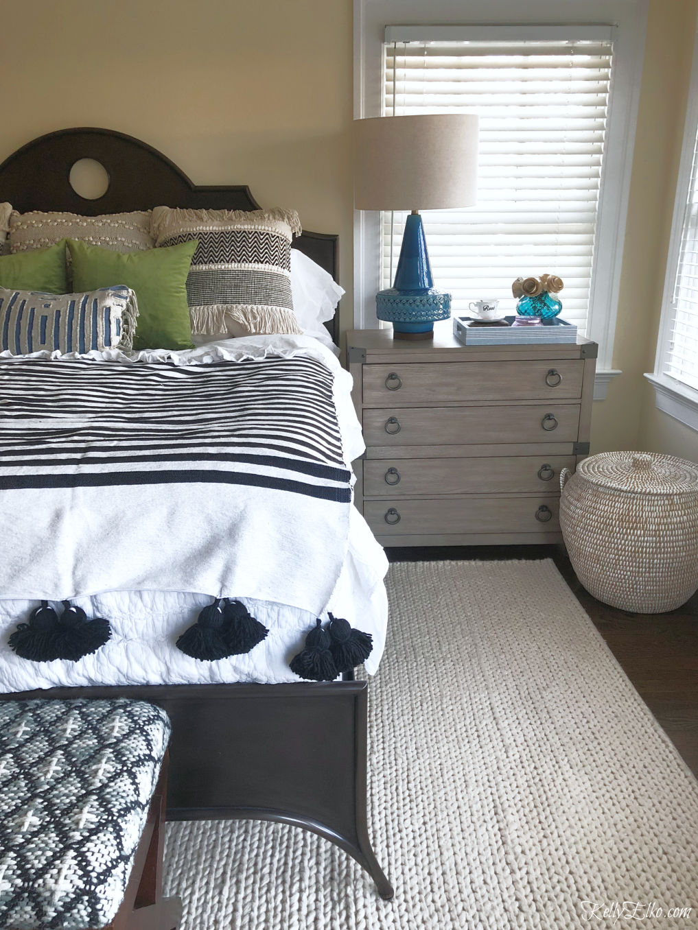 Love this bedroom and the fun tassel blanket and chest of drawers as a nightstand kellyelko.com #bedroom #bedroomdecor #bedding #boho #eclecticdecor #interiordecor #midcentury