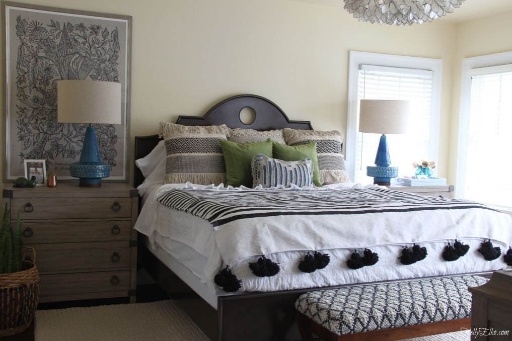 Beautiful bedroom with lots of texture from tassels, fringe, ruffles and velvet. Love the oversized art and the chest of drawers used in place of a nightstand. kellyelko.com #bedroom #bedroomdecor #bedroomfurniture #bohostyle #bohodecor #eclecticdecor #bedding #nightstands #interiordecor #interiordecorate #bedroommakeover #lighting 